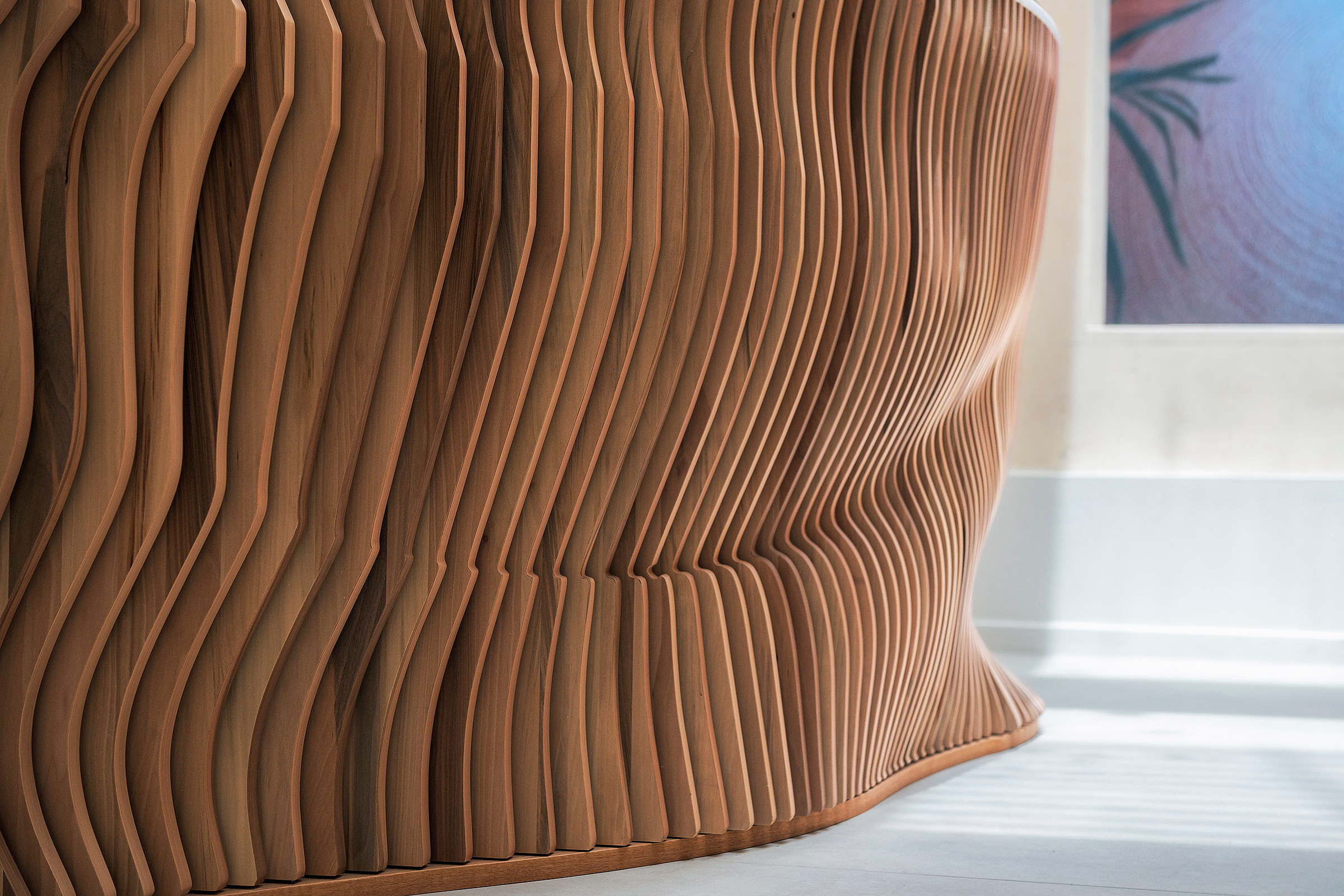 Dettaglio delle lamelle di legno che disegnano il profilo organico del banco reception.