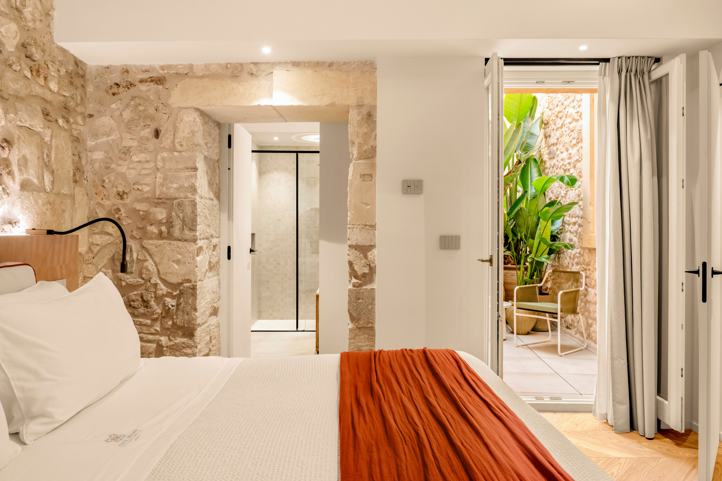 Camera con letto e una sequenza di aperture verso il bagno e lo spazio esterno.