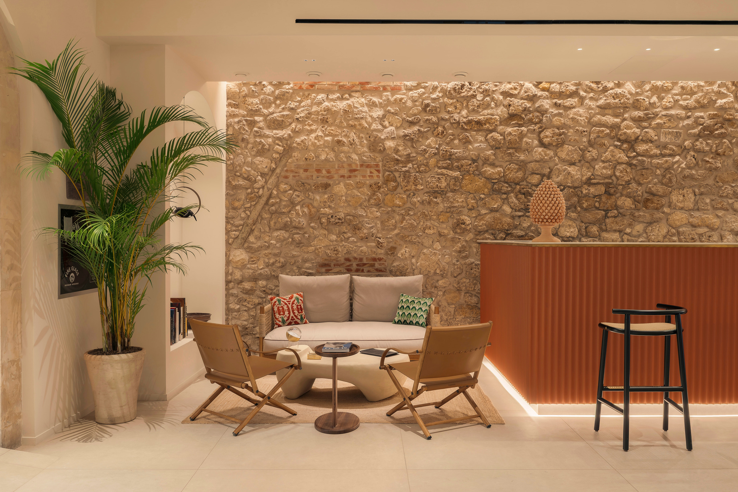 Il salotto e il banco bar in terracotta, davanti alla muratura storica di Cool Dreams Ortigia.